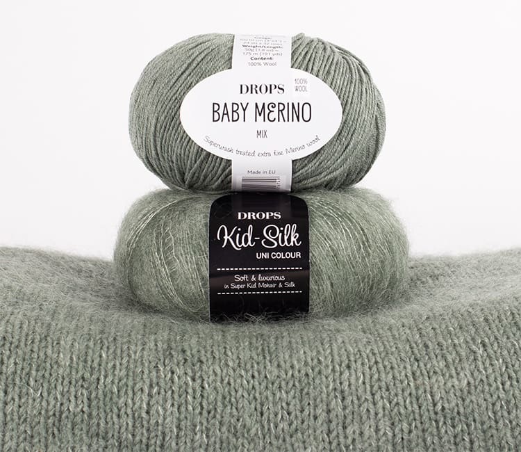 Sage green Kids Silk and sage green baby merino sitting on top of a knitted jumper made from the same yarn.